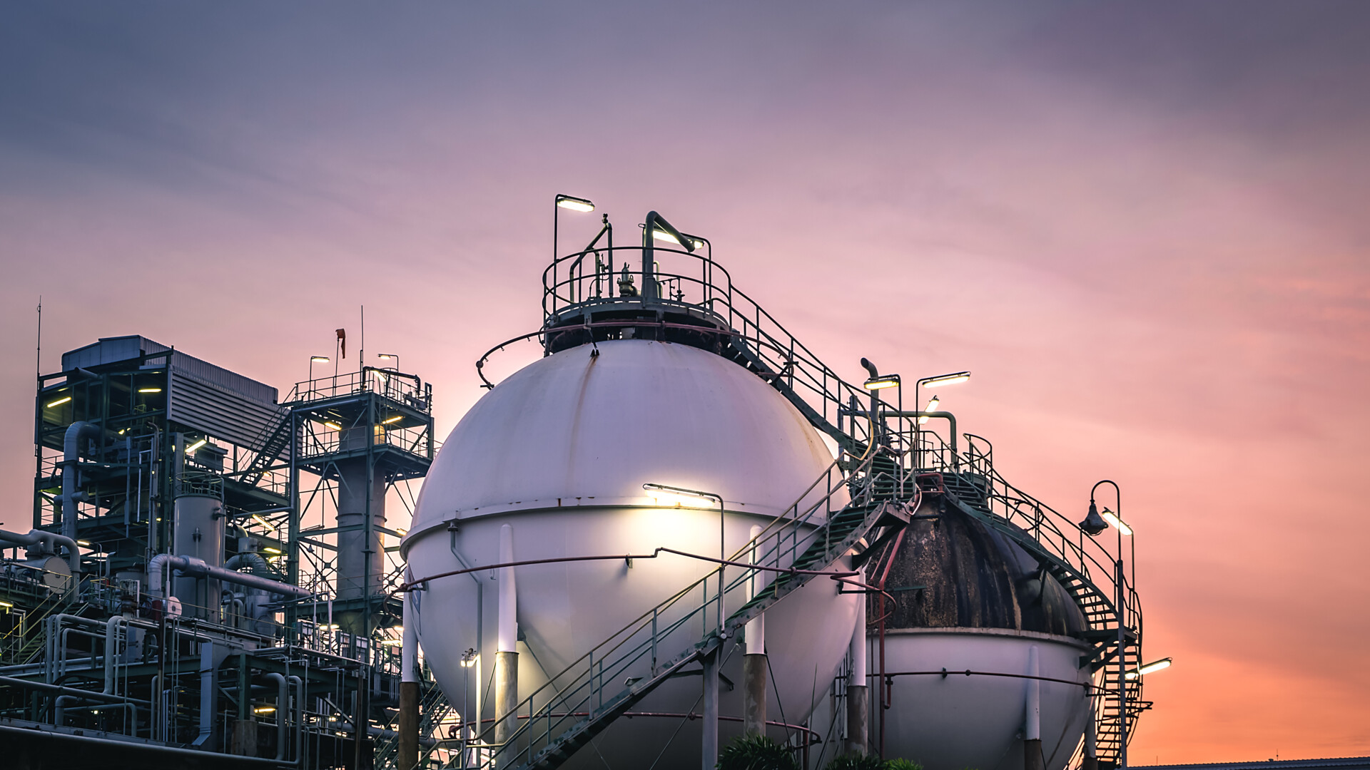 Stalowy zbiornik świeci w zmierzchu na fabryce.