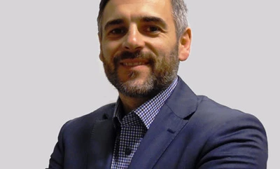 Mężczyzna z zarostem na twarzy i tatuażem na rękawie patrzy w dal, prezentując swoją mocną linię żuchwy i wydatne kości policzkowe.