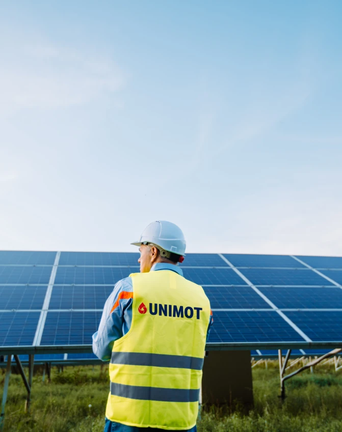Robot budowlany w ubraniu o wysokiej widoczności i kasku reprezentuje zaangażowanie UNIMOT w bezpieczeństwo i czystość placu budowy. Ten inżynier jest częścią zespołu dedykowanego tworzeniu zrównoważonych projektów, takich jak systemy energii słonecznej.